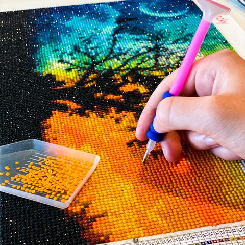 Person working on a diamond painting project with a close-up of the artwork and tools.